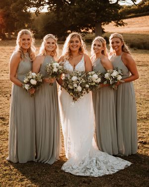 Bridesmaids in sage green pleated bridesmaid dress with the bride for a rustic barn wedding.