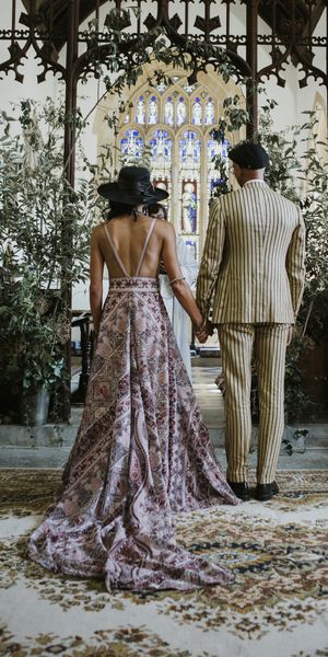 bride and groom wearing pink boho wedding dress and pinstripe groom suit stand at the altar facing away from guests