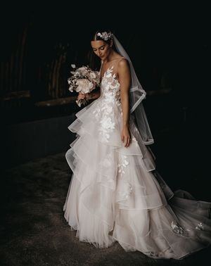 Bride in a layered tulle Wtoo by Watters wedding dress and flower hairpiece.