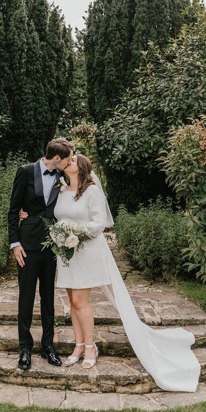The bride wears a short wedding dress with bow with the from in black tux for wedding.