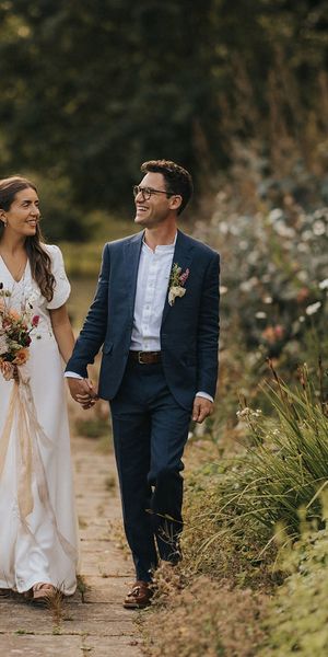 Bride holding bouquet of rustic wedding flowers with the groom for Askham Hall wedding.