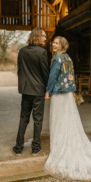 Groom in black tie with bride in lace Rosa Clara dress and bespoke embroidered denim jacket. 