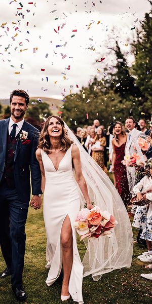 Bride in Suzanne Neville wedding dress with groom in blue suit have confetti exit from outdoor wedding at Rossie On The Earn venue. 