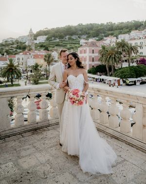 bride and groom stand on a balcony with Old Town Hvar in the background at destination wedding in Croatia