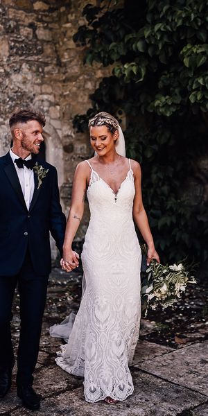 Bride in lace wedding dress and groom in black tie walk together at Athelhampton House.