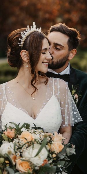 Bride in a dotted wedding dress and quartz crystal crown with the groom in a velvet suit jacket.