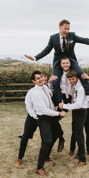 Groom sitting on groomsmen's shoulders for festival-themed wedding