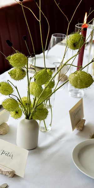 White bud vases with green florals and blooms with place names