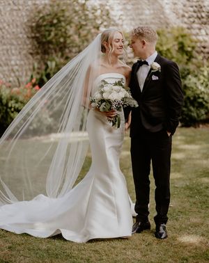 Mermaid wedding dress worn by the bride standing with groom in black tux