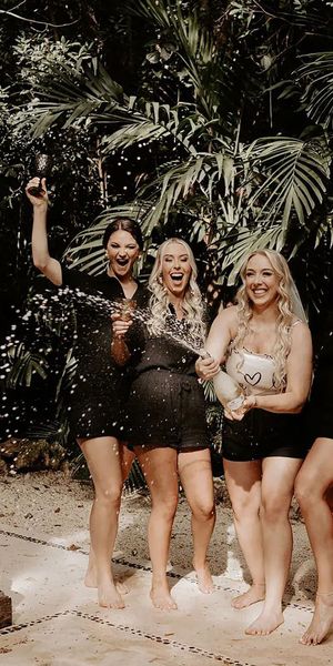 Bridal party wearing matching black pjs spraying champagne for hen do