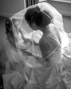bride wearing ethical wedding dress and veil holding hands with a child
