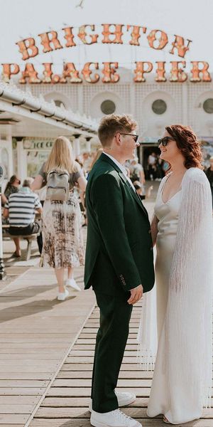 Couple getting married in Brighton with the iconic pier sign behind them
