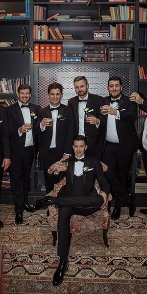 groom and groomsmen taking group photo on wedding day wearing matching black tuxedos