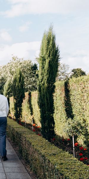 Modern romance meets classic English charm, the couple wander through a serene garden aisle moments after saying “I do”. Photography by Kseniia Photo.