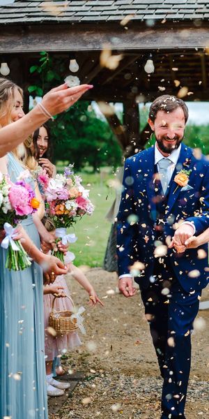 The happy couple walk down the aisle as they are covered in wedding confetti