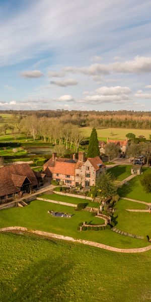 A stunning aerial view of Burrow Farm Estate, showcasing the beautifully restored main house and barn nestled within rolling countryside, surrounded by manicured gardens, woodland and expansive open fields in the heart of the Chiltern Hills. Image credit: Burrow Farm Estate