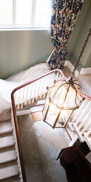 A bride in a flowing white dress descending the stairs of Dunston Hall taken by 21 Photography