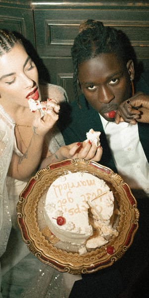 Wedding cake, fingers first. A couple diving into cake on a vintage gold platter, with red lipstick, lace and a playful disregard for etiquette. Your Love, Your Rules. Photography by Alice Santella.