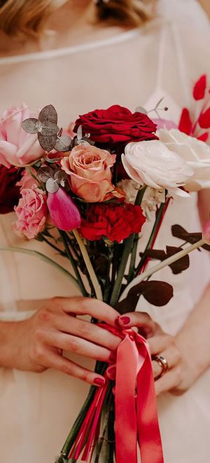 Bridal bouquet with white, pink and red garden roses, pink peonies and red dried decor with pink and red ribbon tied around for Valentine's Day theme wedding