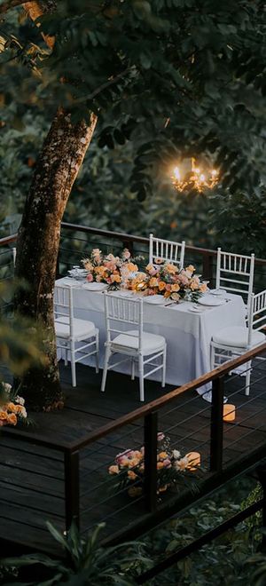 White wedding tablescape and decorations with colourful yellow flowers and pillar candles high in the jungle in Bali