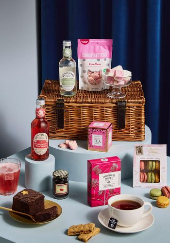 afternoon tea hamper as bridesmaid gift box idea, including sweet treats and tea bags, presented in a classic wicker basket.