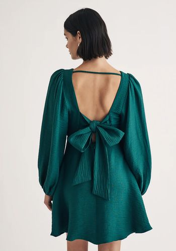 dark green mini winter wedding guest dress, with voluminous sleeves and open back that ties together with bow