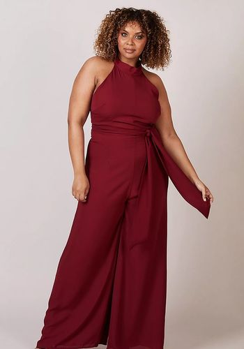 dark red wedding guest jumpsuit with wide leg palazzo trousers, bow neck tie and waist sash tie.