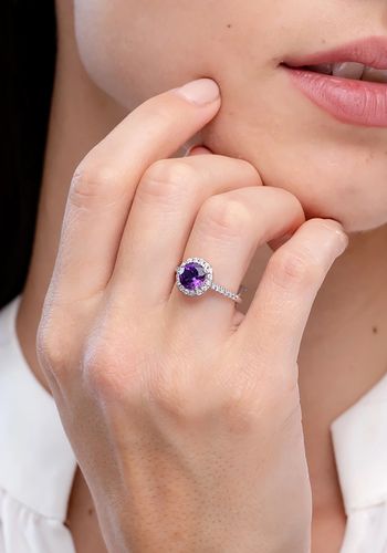 intense purple amethyst in a prong setting is surrounded by a glimmering diamond halo