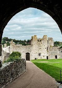 Medieval stone castle ruins framed by an arched gateway in Wales
