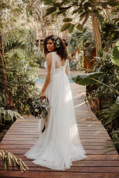 Tulum destination wedding with tropical plants a bride in a floaty dress with naturally curly hair 