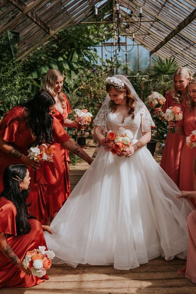 Bride in a princess tulle wedding dress with the bridesmaids in coral peach bridesmaid dresses.