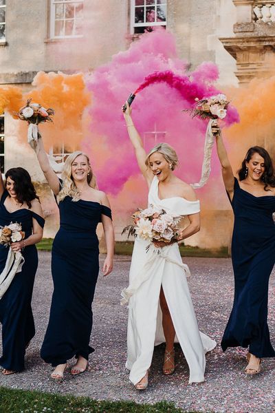 Bride and bridesmaids in navy blue dresses take part in smoke bomb photoshoot for wedding