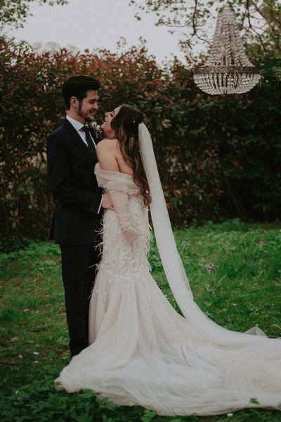 Bride and groom laugh outside next to chandelier decor for their romantic Millbridge Court wedding.