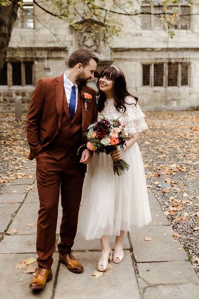 Bride in Needle and Thread top and skirt and groom in brown suit look into each other's eyes on their wedding day. 