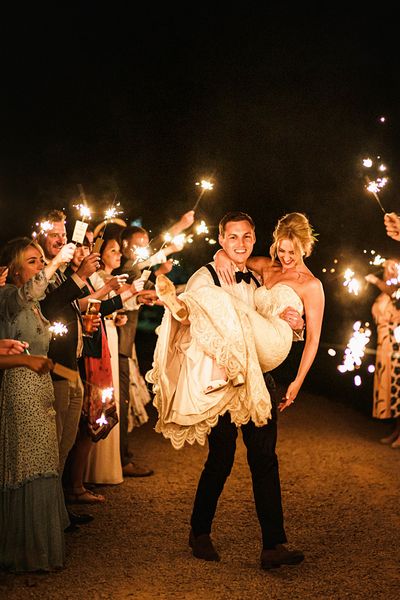 Groom lifting his bride in the air during their sparkler send off 