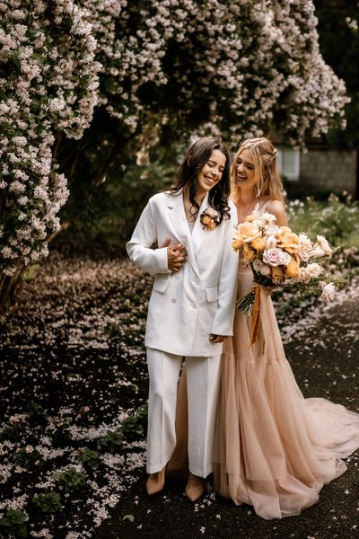 Honey yellow wedding inspiration with two brides in a peach wedding dress  and white bridal suit