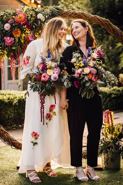 Two brides stand next to moongate decoration at seasonal at The Parlour wedding