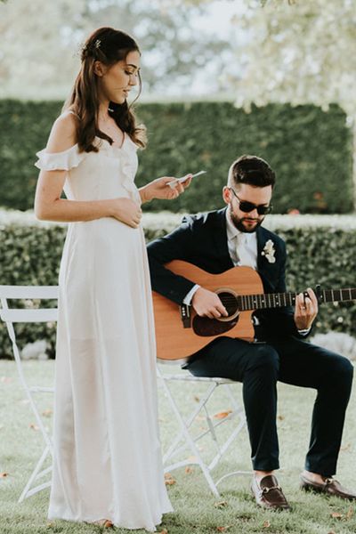 Bridesmaid gives a wedding reading during a ceremony with guitar player.