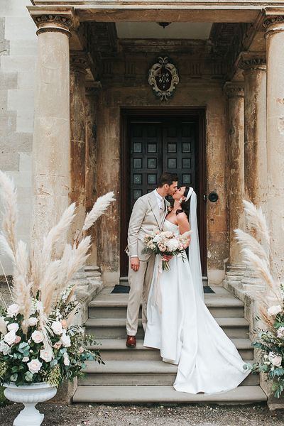 Bride in Jesus Peiro wedding dress and groom in beige suit with pampas grass floral arrangements. 