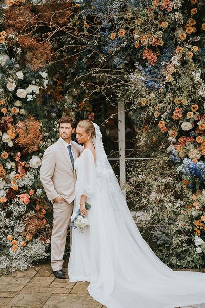 Bride and groom in front of large floral display at Sezincote House.