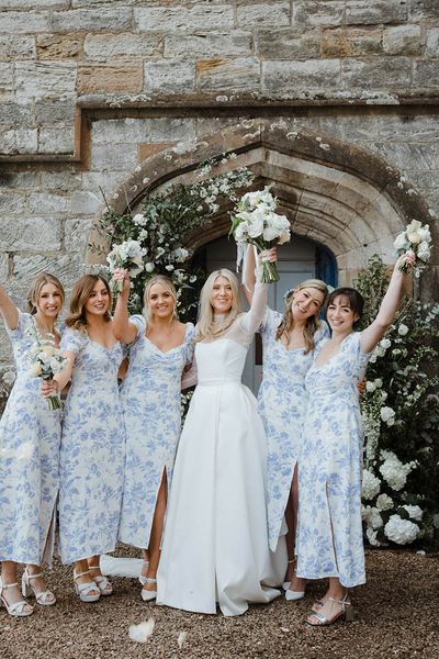 Bride with bridesmaids in blue patterned dresses at their wedding venue.