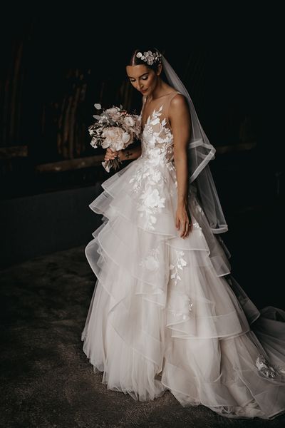 Bride in a layered tulle Wtoo by Watters wedding dress and flower hairpiece.