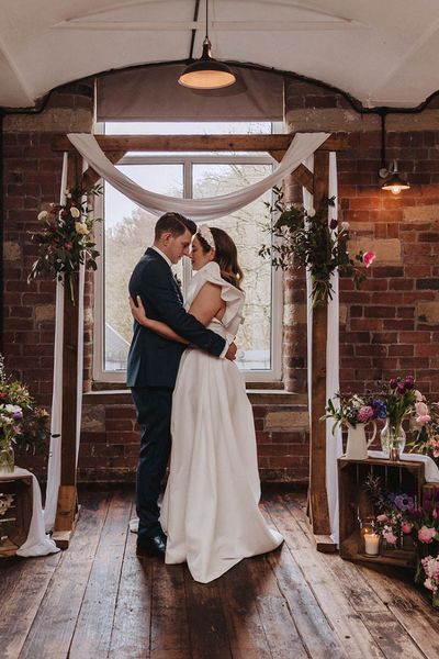 Bowers Mill wedding venue with industrial elements and pretty wildflower decor arranged by the bride herself. Bride wears Jesus Peiro gown and groom wears blue suit.