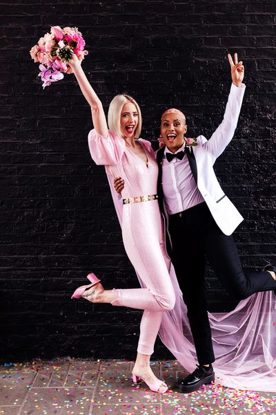 Alternative wedding inspiration with two brides in a pink jumpsuit and white tuxedo jacket 