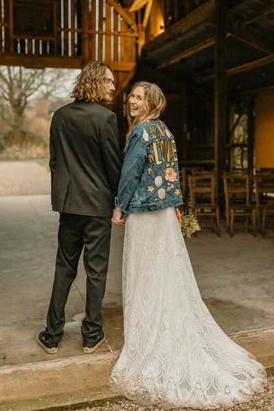 Groom in black tie with bride in lace Rosa Clara dress and bespoke embroidered denim jacket. 