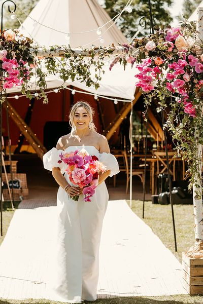 Tipi wedding with the bride in off the shoulder dress holding pink bouquet