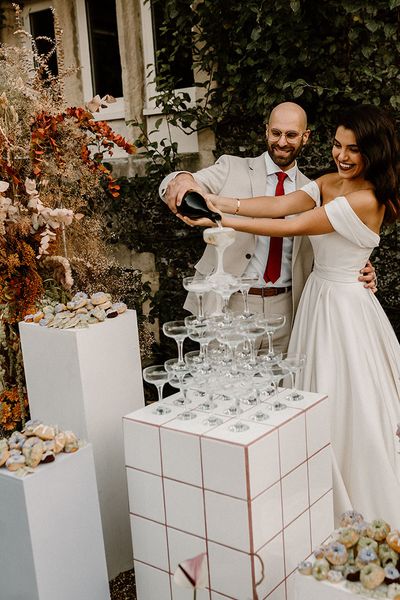 Bride and groom pour their champagne tower for their wedding at Chapel House Estate.