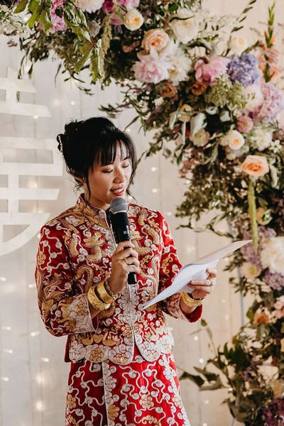 Bride in Chinese wedding attire reading out modern wedding reading