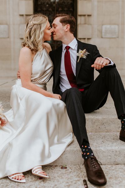 Bride in a champagne colour wedding dress kissing her groom on the steps at Leeds Civic Hall 