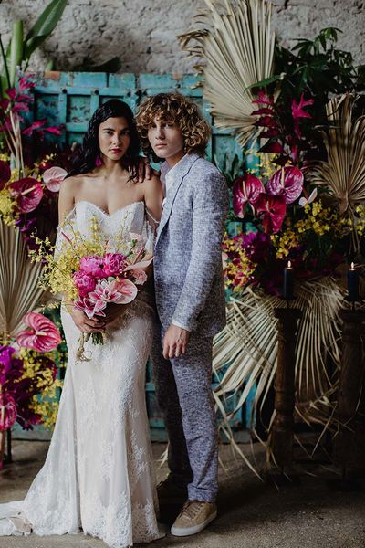 Bride in lace wedding dress and groom in blue suit stand at the altar for their Bali elopement.